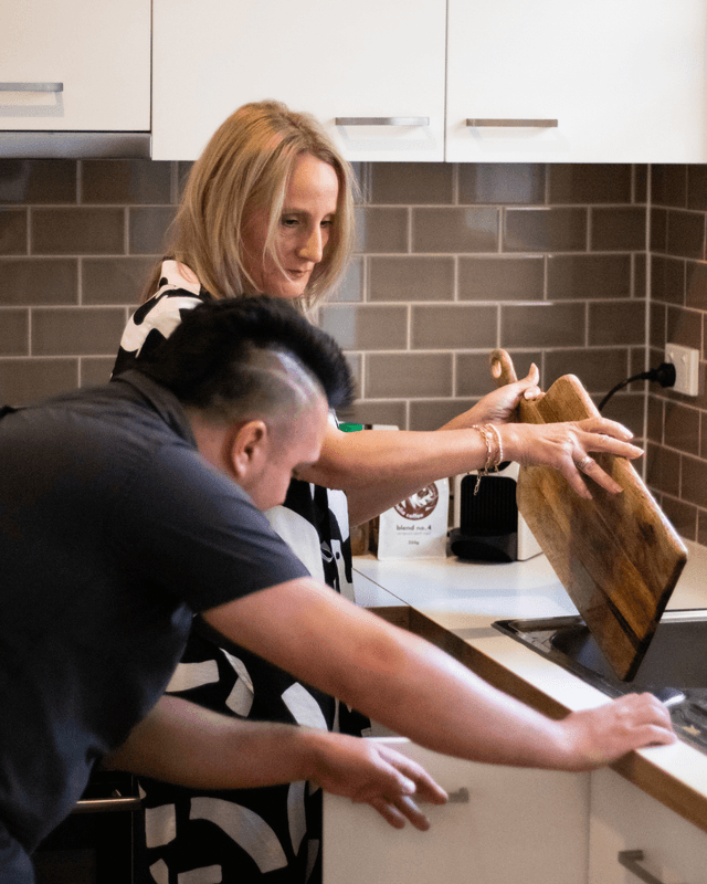 A participant and support worker preparing food together in a kitchen